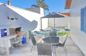 Enjoy al fresco dining with a pizza oven, seating area, and umbrella shade.