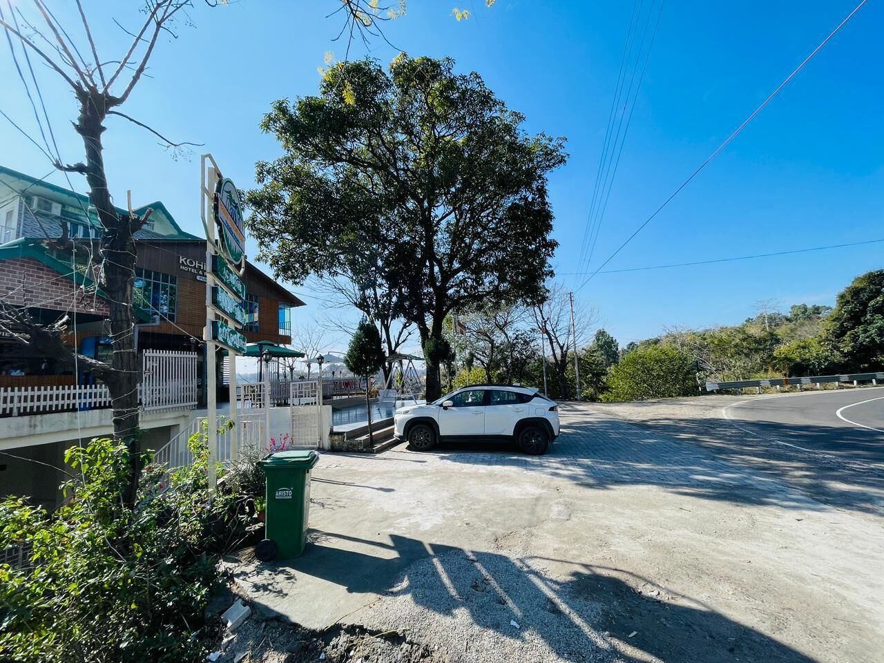 A white car parked near a building with a sign that reads 'Kohino Hotel.'