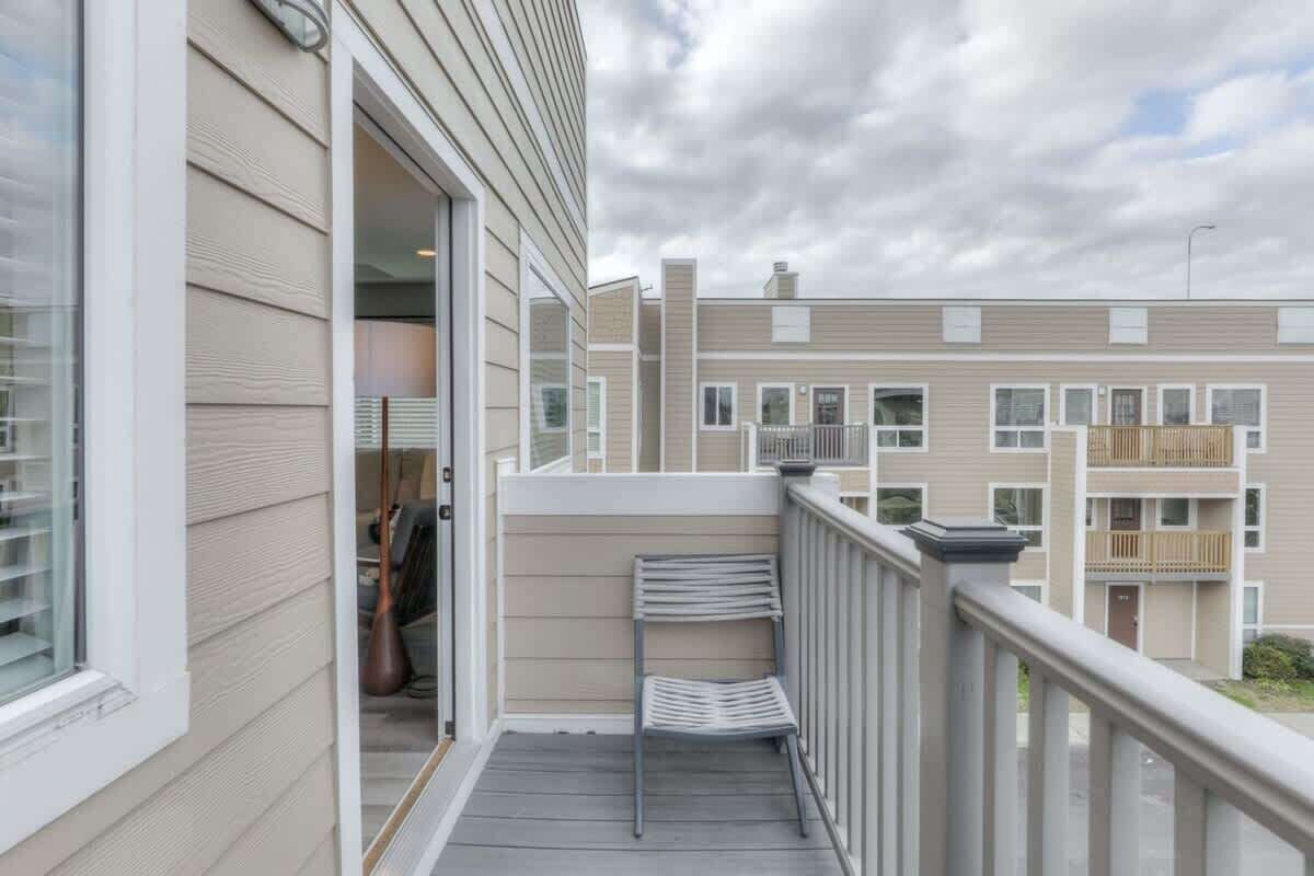 A balcony with a metal chair, a small table, and a view of a multi-story building.