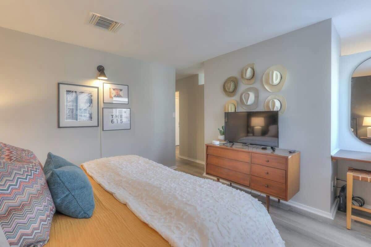 Un dormitorio con cama, cómoda, televisor y adornos en la pared.