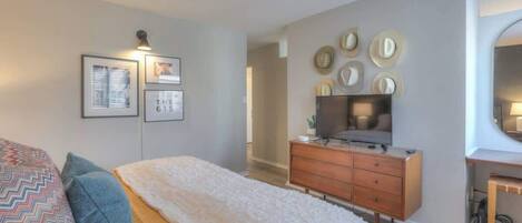 Un dormitorio con cama, cómoda, televisor y adornos en la pared.