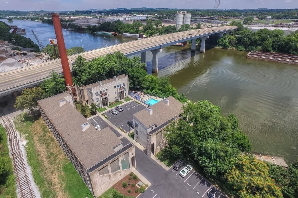 An industrial area with a bridge over a river, buildings with parking, and a swimming pool.