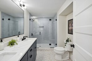 A modern bathroom with a glass-enclosed shower, a white toilet, and a marble vanity. - 6BR Classic Boston Home | Near Savin Hill T (Boston)