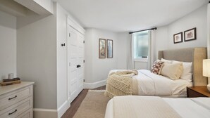 A bedroom with a bed, a nightstand, a dresser, and a window with curtains.