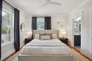 A bedroom with a large bed, two bedside tables, a ceiling fan, and a view of the bathroom. - 6BR Classic Boston Home | Near Savin Hill T (Boston)
