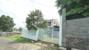 A paved pathway leading to a gated area with a stone wall and a metal fence. - Hotel O Kencana Homestay Syariah Near Masjid AL-BAROKAH Kanyuran (Mojokerto)