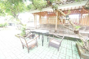 An outdoor patio with a table and chairs, surrounded by stone steps and greenery. - Hotel O Kencana Homestay Syariah Near Masjid AL-BAROKAH Kanyuran (Mojokerto)