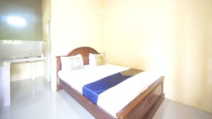 A single bed with a wooden headboard, a white mattress, and a blue bedspread. - Hotel O Kencana Homestay Syariah Near Masjid AL-BAROKAH Kanyuran (Mojokerto)