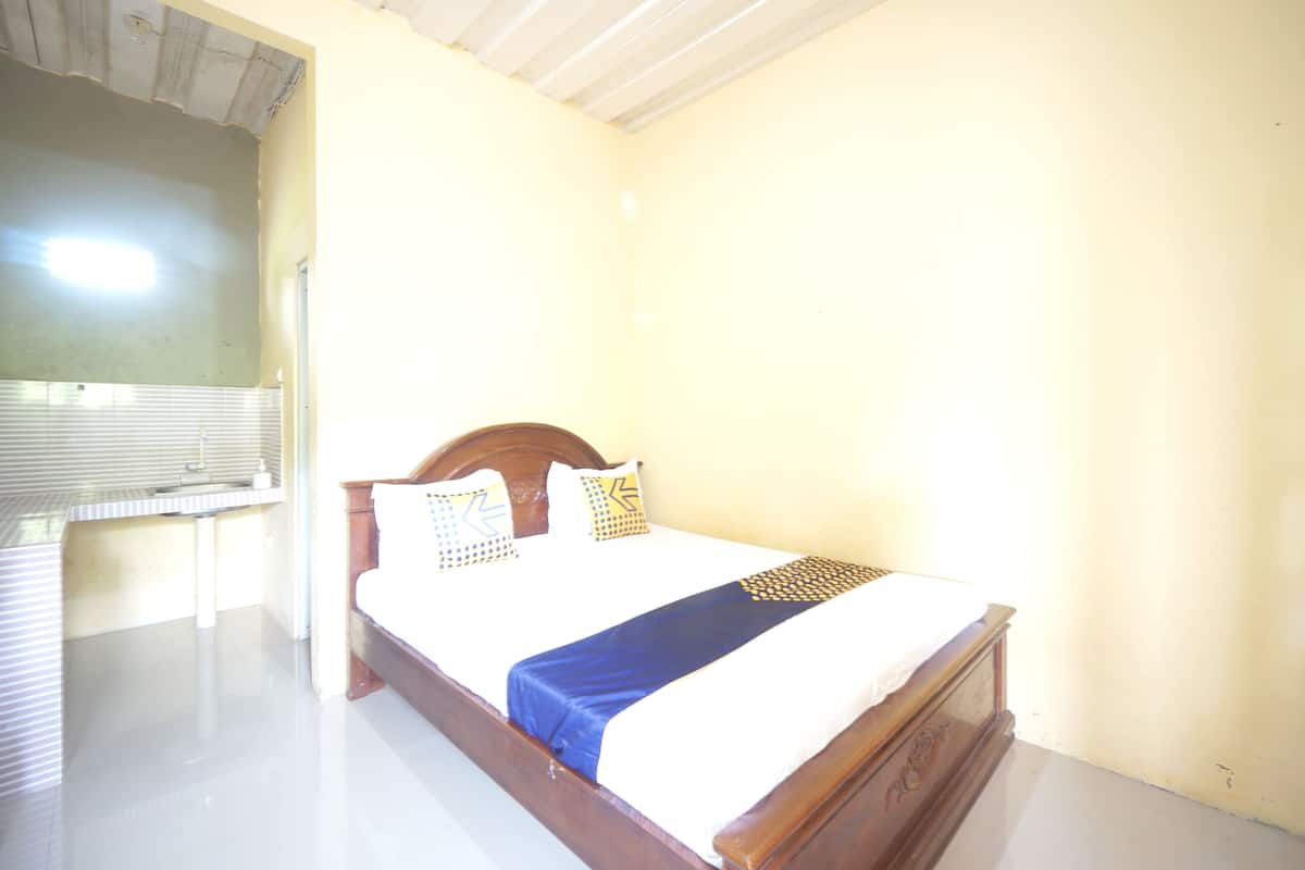 A single bed with a wooden headboard, a white mattress, and a blue bedspread.