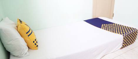 A bed with a white sheet, a yellow pillow with blue patterns, and a blue and yellow checkered blanket.