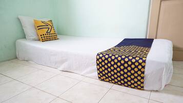 A single bed with a white mattress and a blue and yellow polka dot blanket.