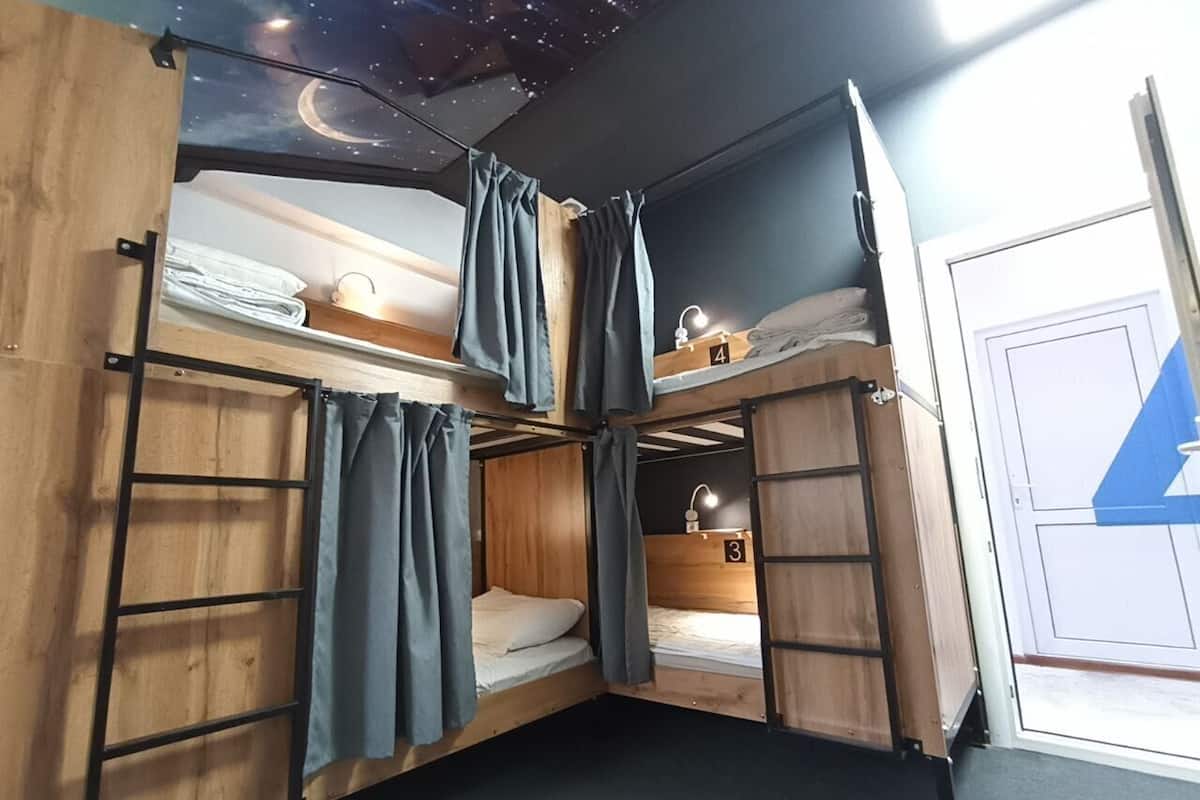 Ein Schlafraum mit Etagenbetten, einem Sternenhimmel-Design, Holzwänden und einer Tür mit einem blau-weißen Schild.