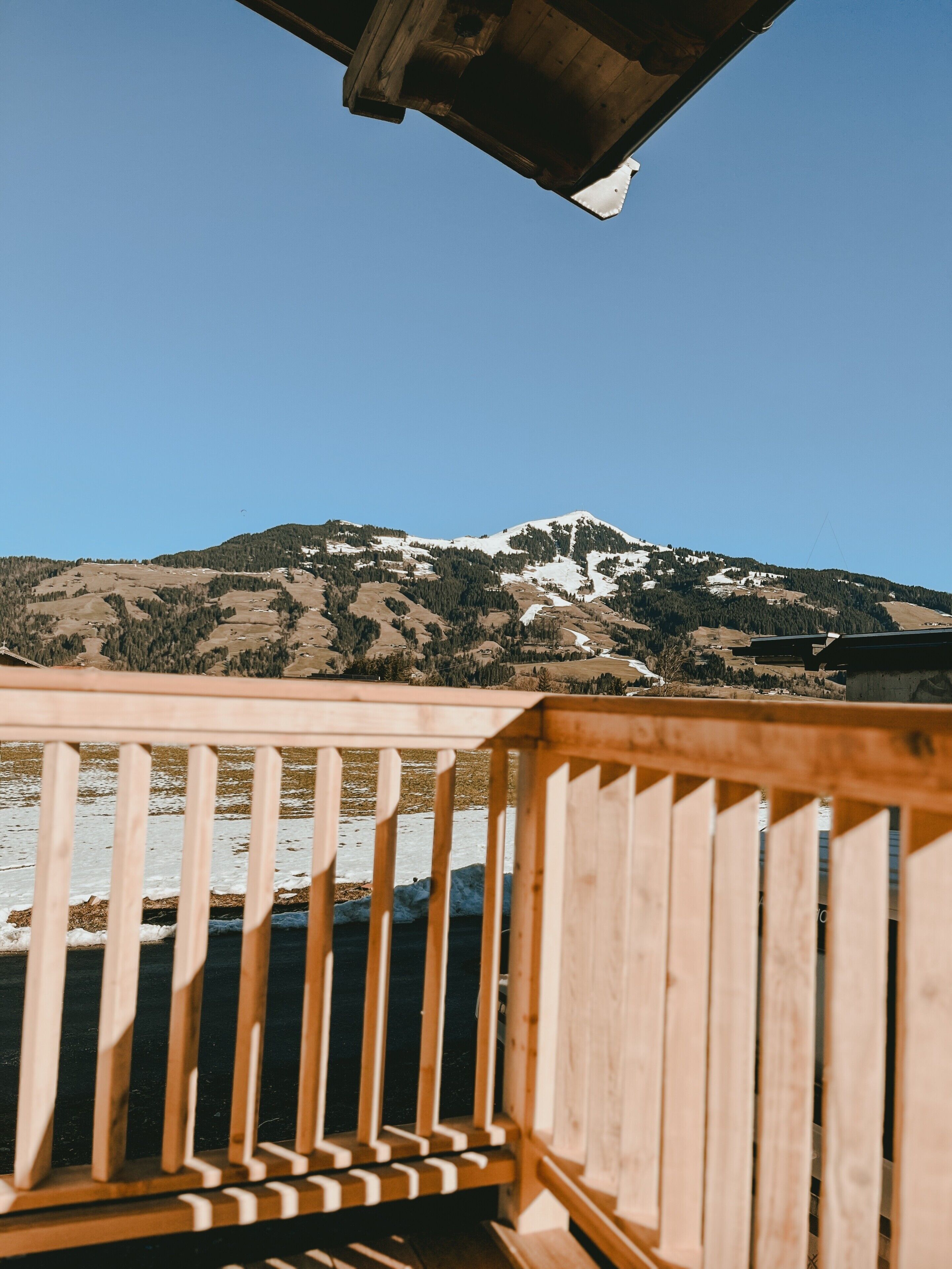 A wooden deck with a view of a snow-capped mountain and a clear sky.