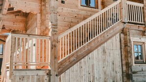 A wooden cabin with a staircase leading to a balcony. - Apartment 'Katie' with Mountain View, Private Terrace and Wi-Fi (Hopfgarten)