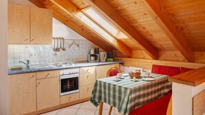 Una cocina con armarios de madera, una estufa y una mesa de comedor con mantel a cuadros.