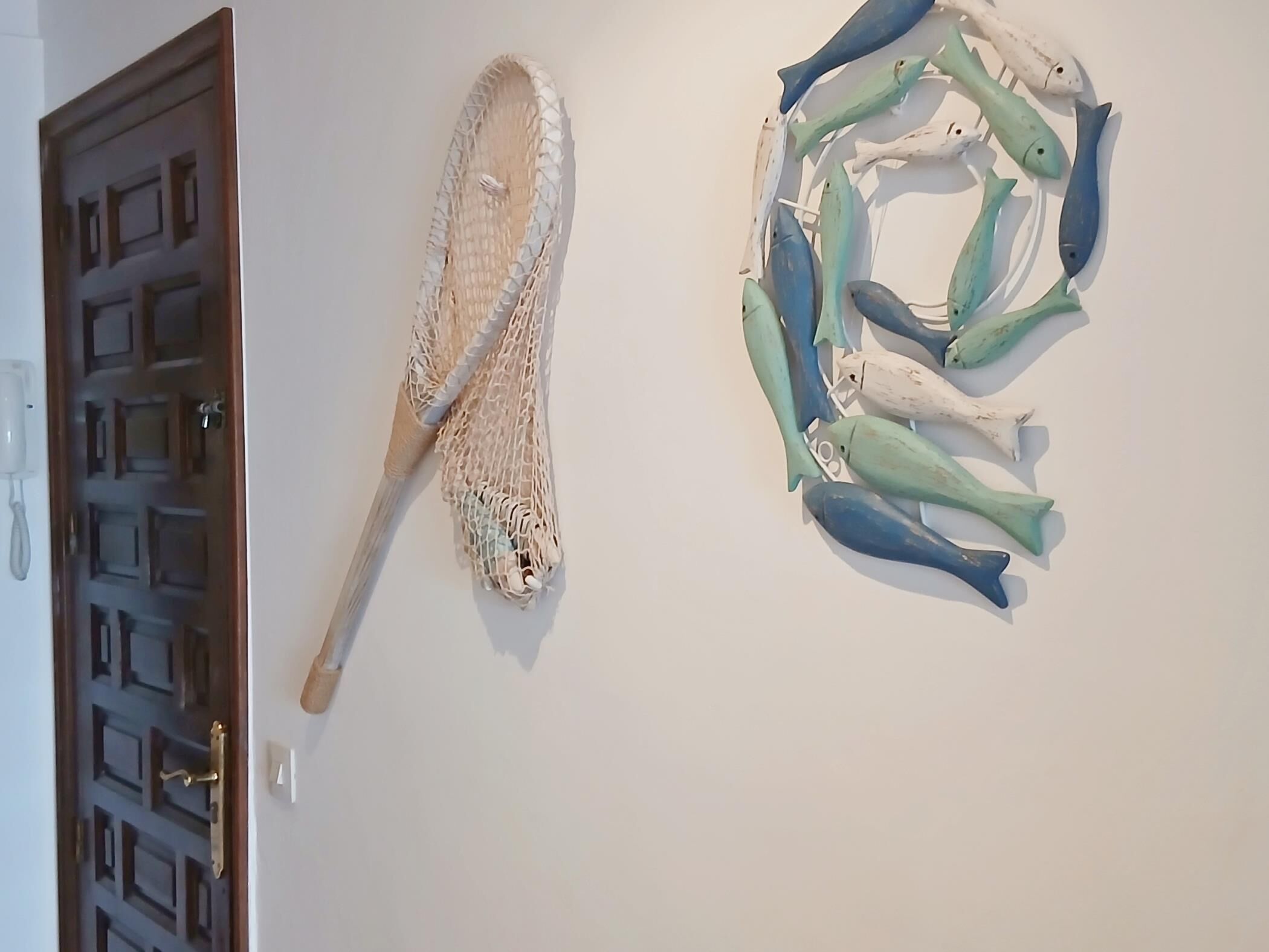 Une porte ornée d’un motif géométrique et un mur sur lequel est sculptée une représentation de poisson.