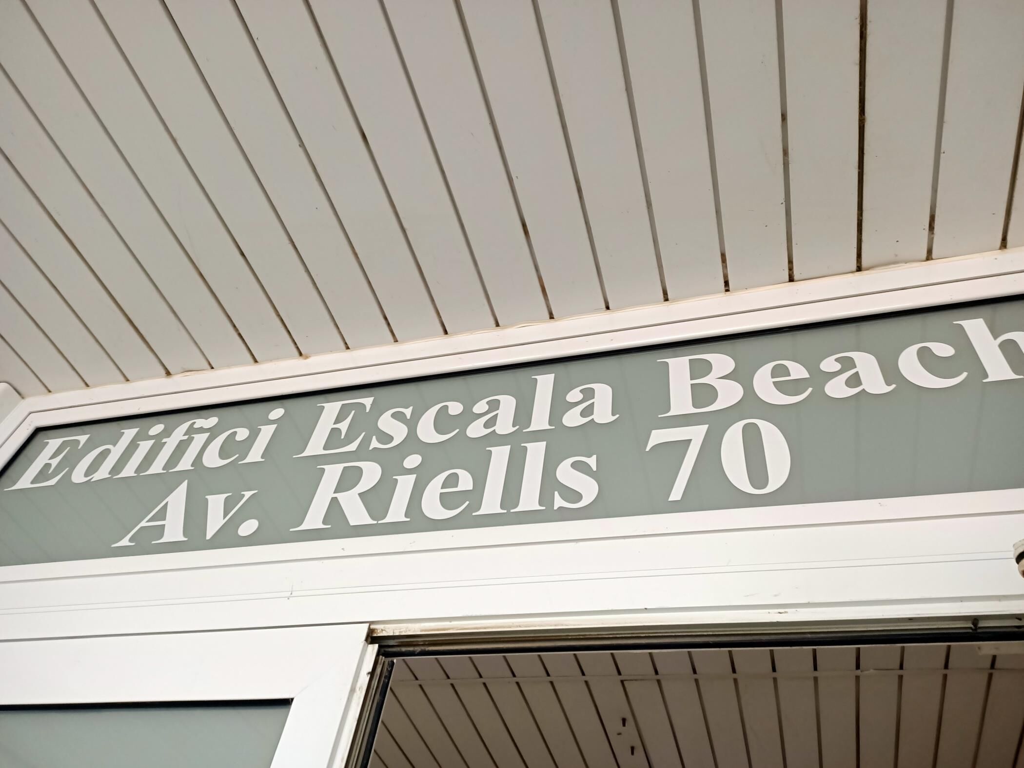 Ein Gebäudeschild mit dem Text 'Edifici Scala Beach Av. Riells 70'.