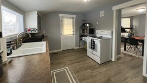 Een moderne keuken met een ingebouwde oven, een spoelbak en een eethoek met een tafel en stoelen.