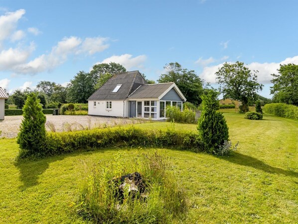 A two-story house with a sloped roof, a front porch, and a well-maintained lawn.