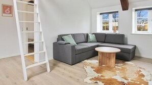 A modern living room with a grey sectional sofa, a wooden coffee table, a cowhide rug, and a white ladder against the wall. - "Thrine" - 24km from the sea by Interhome (Bredebro)