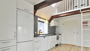 A modern kitchen with white cabinets, a black countertop, and a wooden floor. There is a window with a view of the outside, and a white door leading to another room. - "Thrine" - 24km from the sea by Interhome (Bredebro)