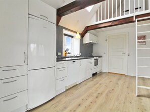 Een koelkast, een vaatwasser, kookgerei, borden en bestek