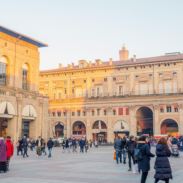 A historic square with a large building featuring multiple arches and a central open space.