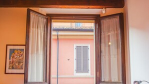 Ein Schlafzimmer mit Bett, Heizkörper, einem Fenster mit Vorhängen und einem hölzernen Kopfteil.