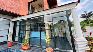 Un edificio moderno con amplios ventanales, fachada roja y plantas en macetas en el suelo.