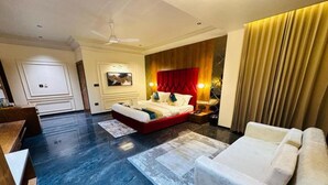 Habitación de hotel con una cama grande, un sofá, un escritorio y un ventilador de techo.