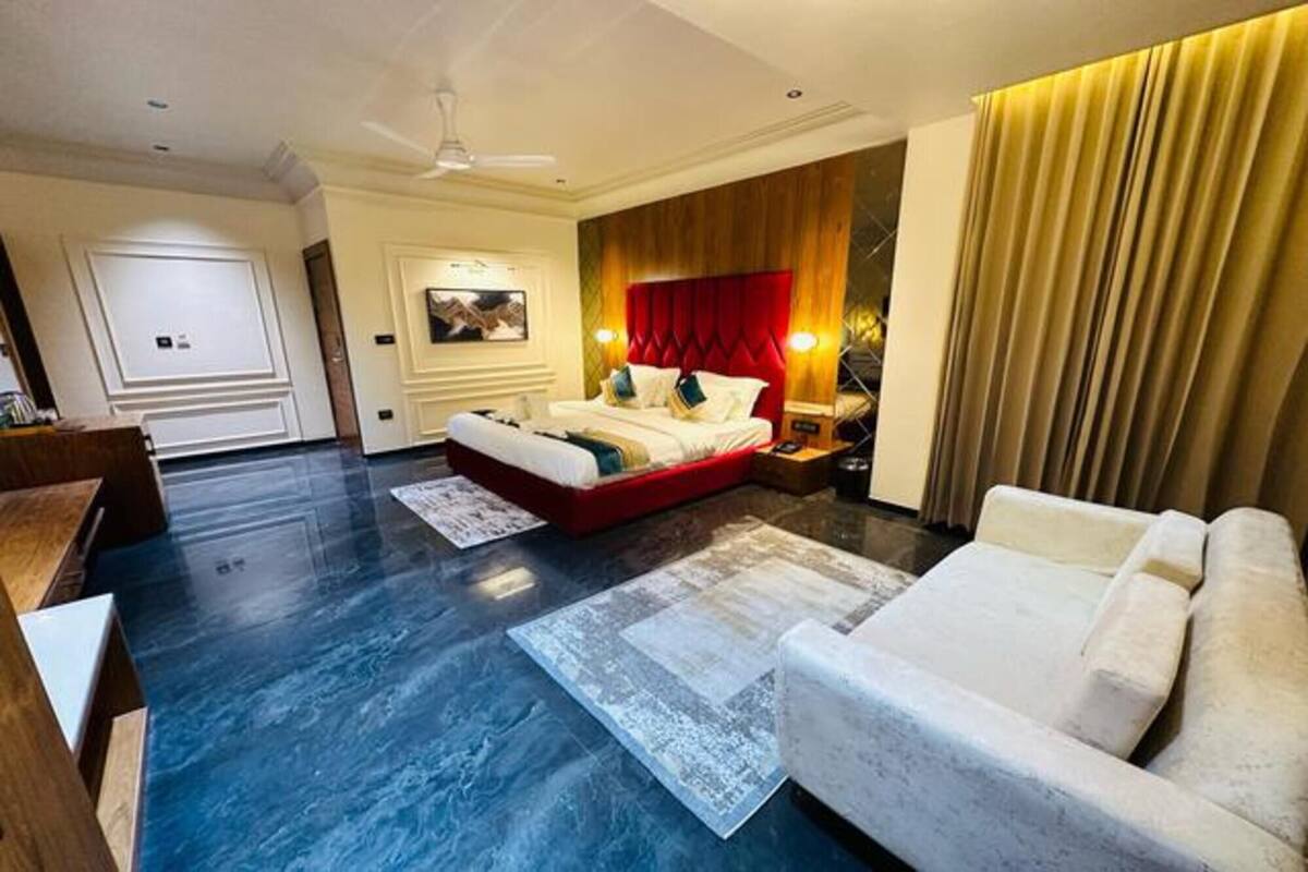 Habitación de hotel con una cama grande, un sofá, un escritorio y un ventilador de techo.