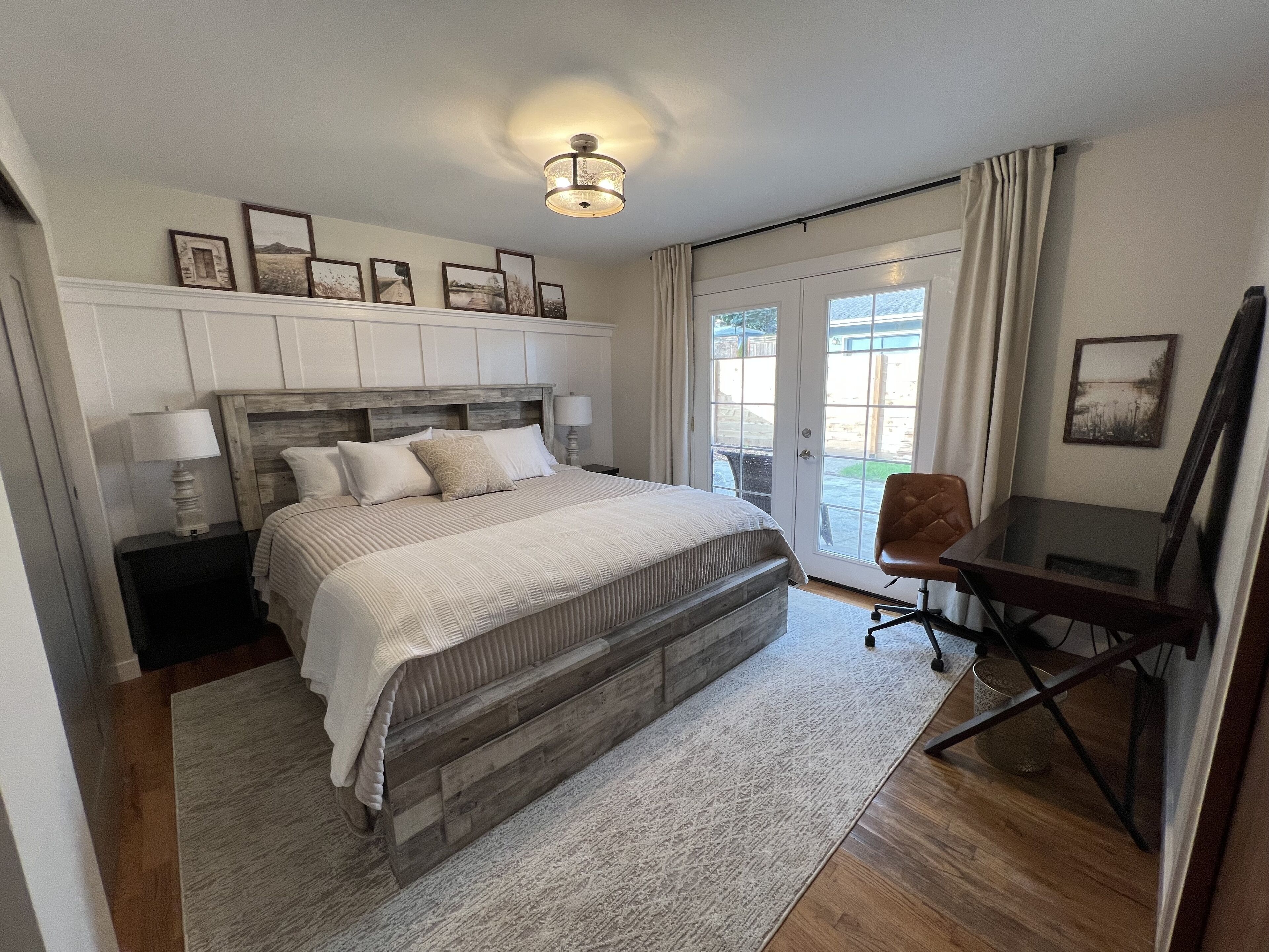 Une chambre avec un grand lit, un bureau et une vue sur l’extérieur, visible à travers une porte vitrée.