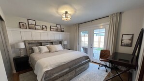 Ein Schlafzimmer mit einem großen Bett, einem Schreibtisch und Blick durch eine Glastür.
