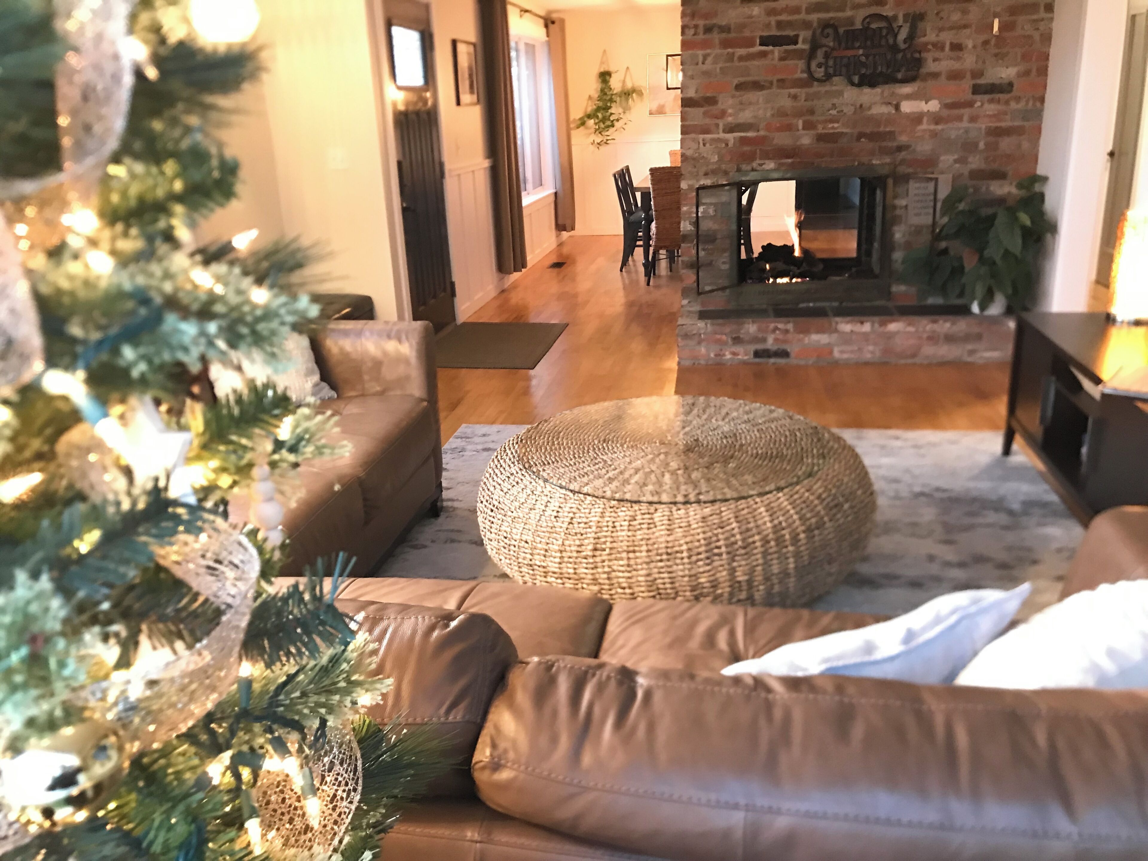 Un salon avec une cheminée, un sapin de Noël et un canapé en cuir marron.