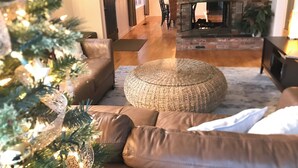 Ein Wohnzimmer mit Kamin, Weihnachtsbaum und braunem Ledersofa.