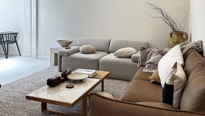 A modern living room with a sectional sofa, a coffee table, and a dining area with a chair and table.