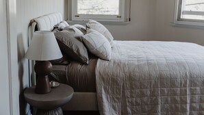 A bedroom with a bed, pillows, a lamp, and a window.