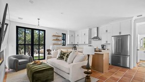 En moderne, åben stue med sofa, skammel og spiseplads.