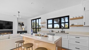 Una cucina moderna con una grande isola, sgabelli da bar, forno integrato e un'area pranzo con divano.