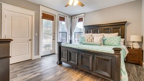 A bedroom with a dark wooden bed, a ceiling fan, and a view of the outdoors through a door. - Jonestown Condo on Lake Travis w/ 2 Balconies! (Jonestown)