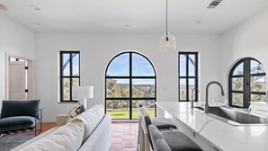 A modern kitchen with a central island, large windows, and a view of the outdoors. - Villa 6 / 3BR / Pool / Hot tub / Firepit / Cornhole (Spicewood)