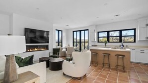 Una sala de estar moderna con chimenea, asientos cómodos y una zona de cocina con taburetes de bar.