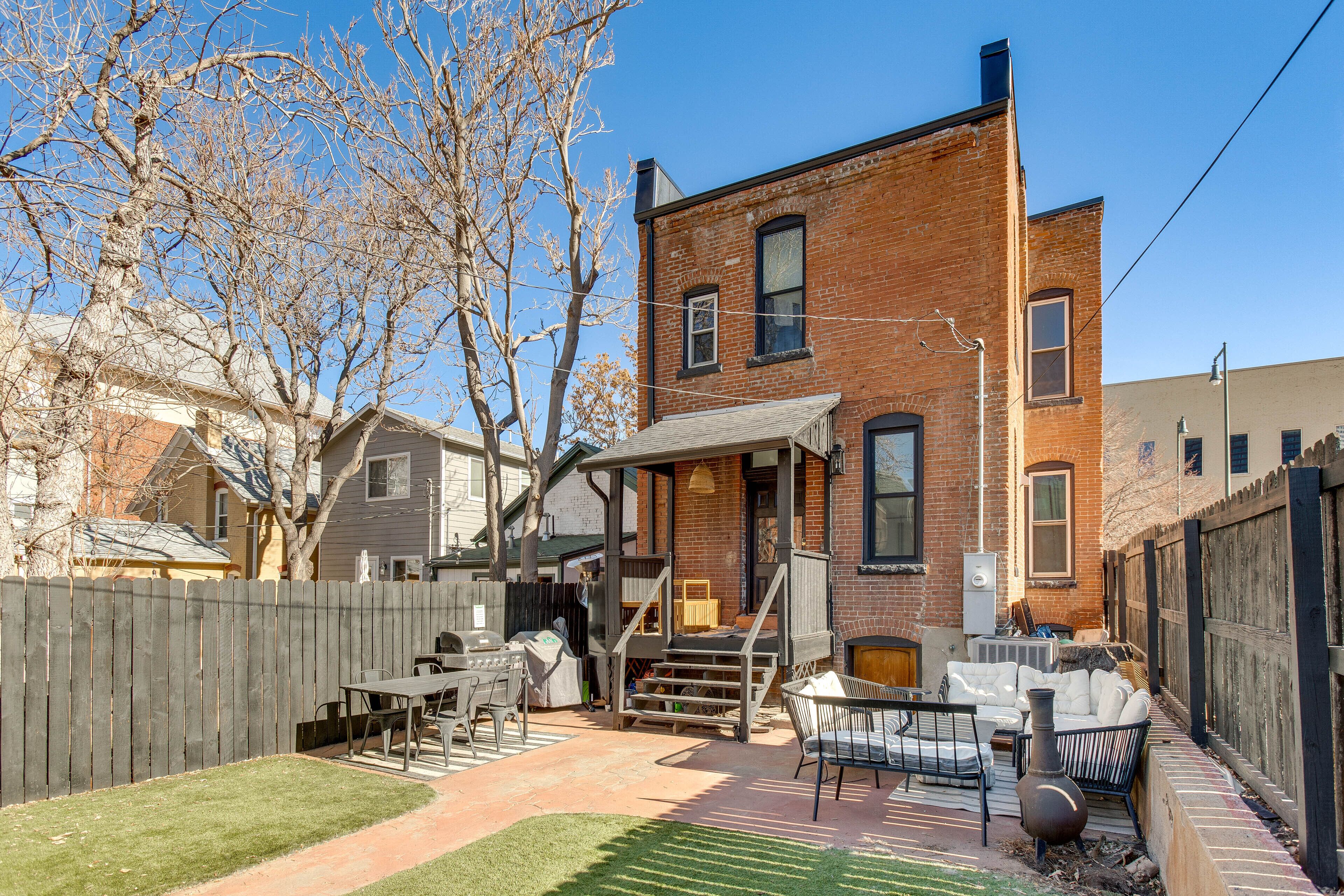 A backyard with a barbecue area, a covered seating area, and a brick house.
