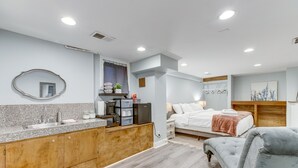 Un dormitorio moderno con una cama grande, mesitas de noche y una silla tapizada en gris.