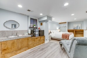 Ein modernes Schlafzimmer mit einem großen Bett, Nachttischen und einem grauen, gepolsterten Sessel.