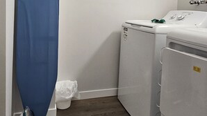 A laundry room with a washing machine, dryer, and ironing board.