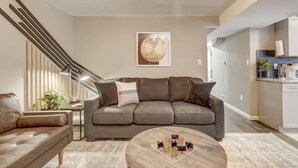 A modern living room with a sofa, a coffee table, and a staircase. - Blackstone Hideaway! Downtown Lower-Level Apt! (Colorado Springs)