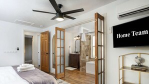 Un dormitorio con cama, ventilador de techo, televisión y baño con ducha y bañera.