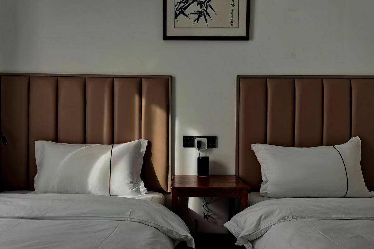A hotel room with two beds, each with a brown headboard and white bedding.
