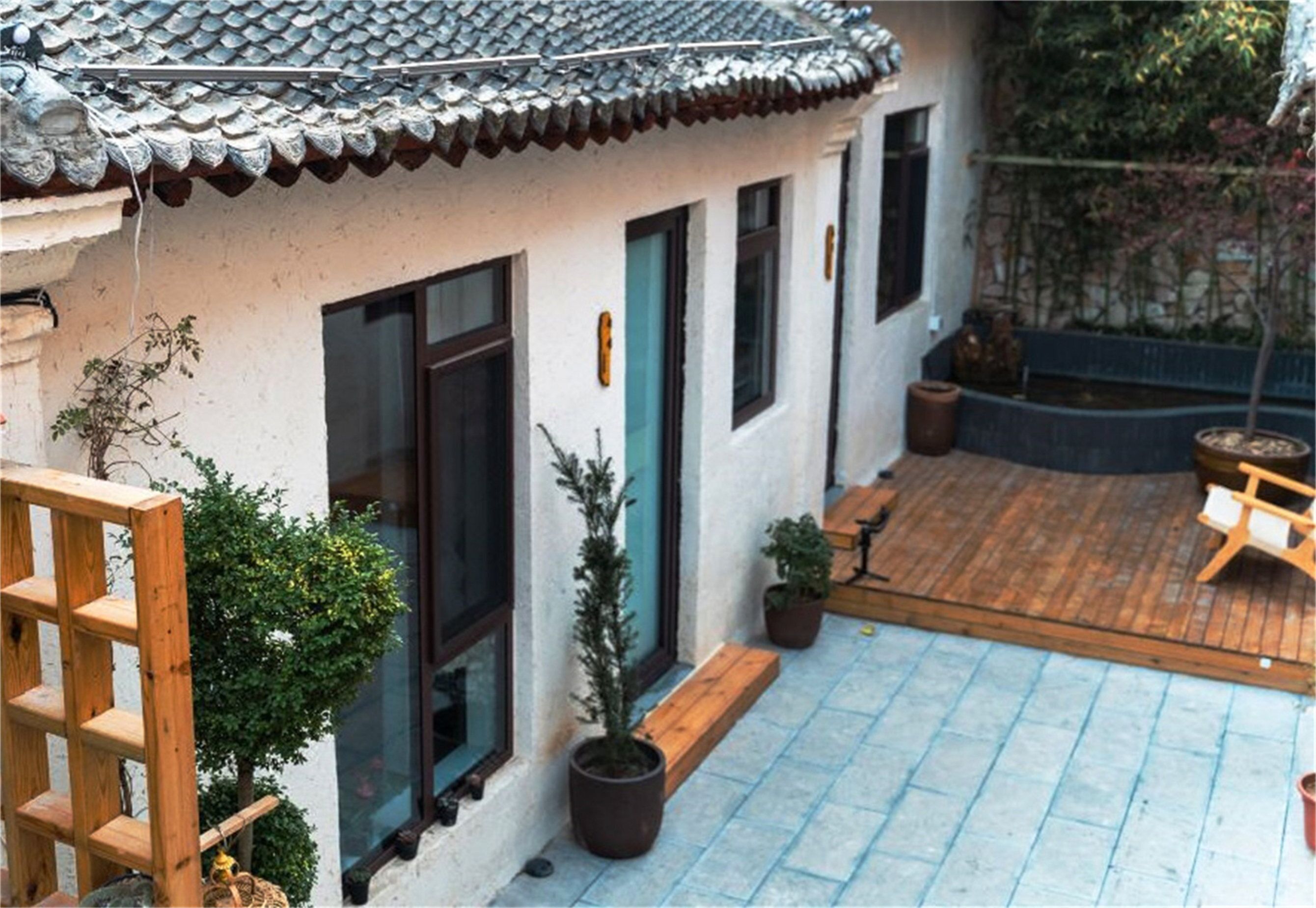 A traditional building with a tiled roof, wooden deck, and potted plants.